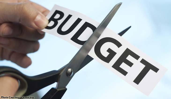 cutting a paper that reads budget